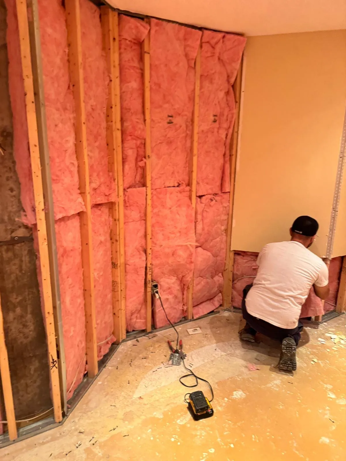 Basement flood cleanup: technician removing wet insulation after a flood cut