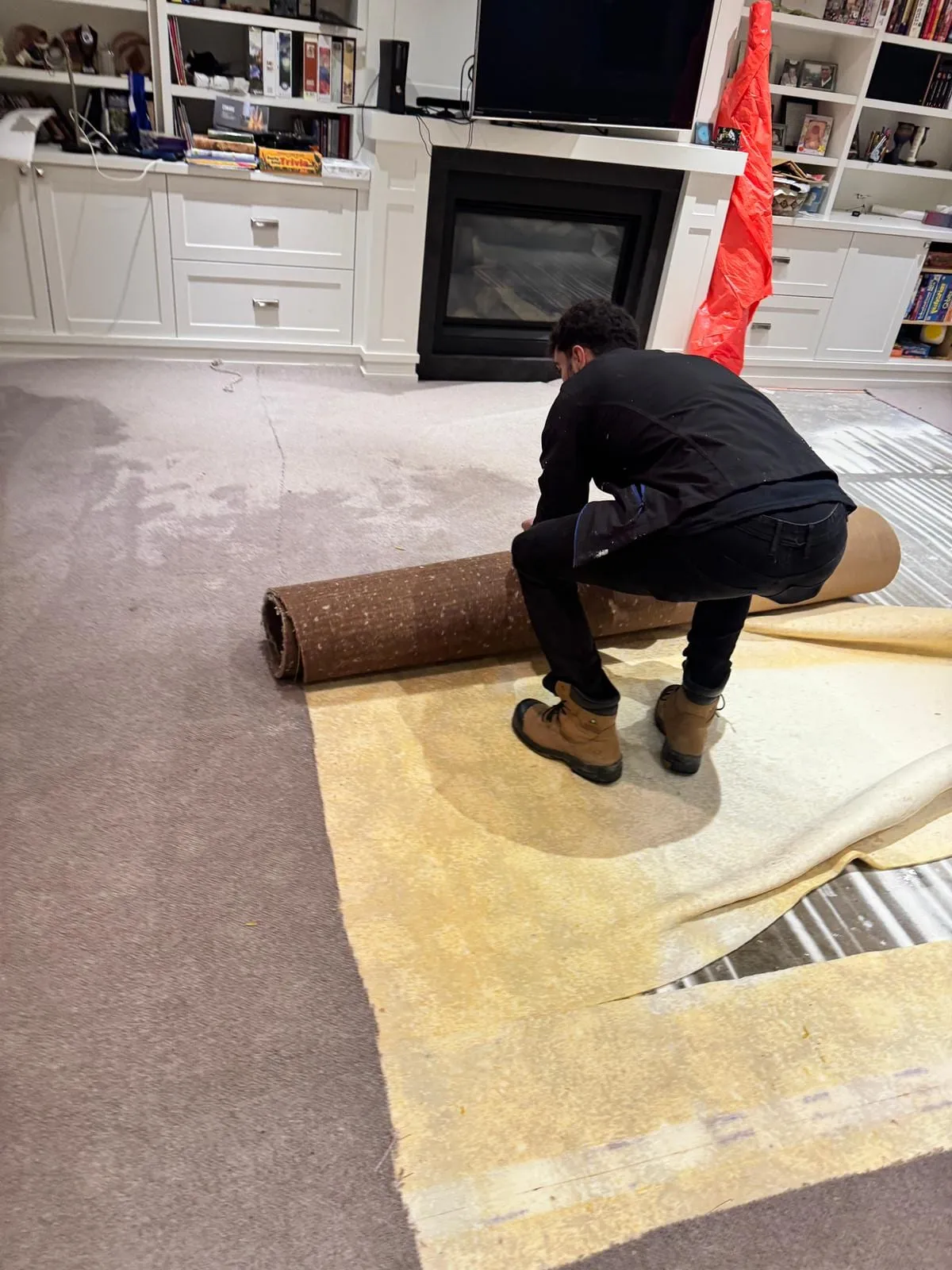 Technician pulling up soaked carpet during emergency water extraction